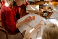 Girl in Red Long Sleeve Shirt Writing on White Paper