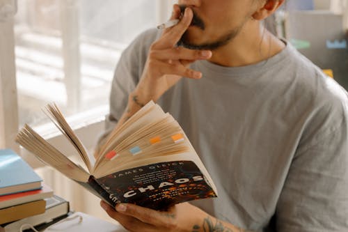 Man in Gray Crew Neck Shirt Holding White and Brown Book