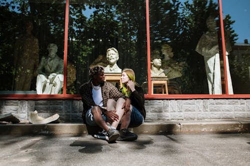 2 Women Sitting on Gray Concrete Floor