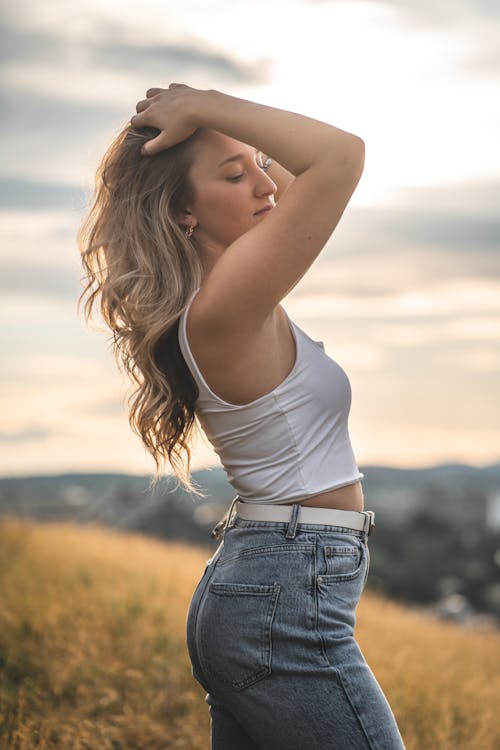 Woman Wearing White Tank Top Standing on Grassland