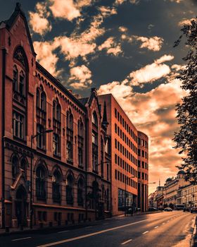 Gothic and modern architecture contrast under a dramatic Warsaw sky at sunset.