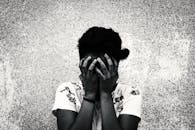 一幅艺术化的黑白肖像中，一名女子遮住脸庞，唤起悲伤或沉思的情绪