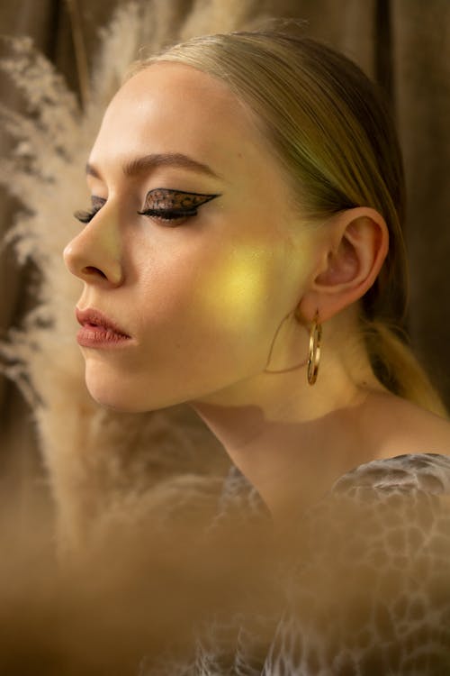 Side view of serious beautiful female with closed eyes and stylish bright makeup