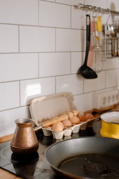 A warm kitchen scene featuring a pan, eggs, and Turkish coffee pot, creating a cozy atmosphere.