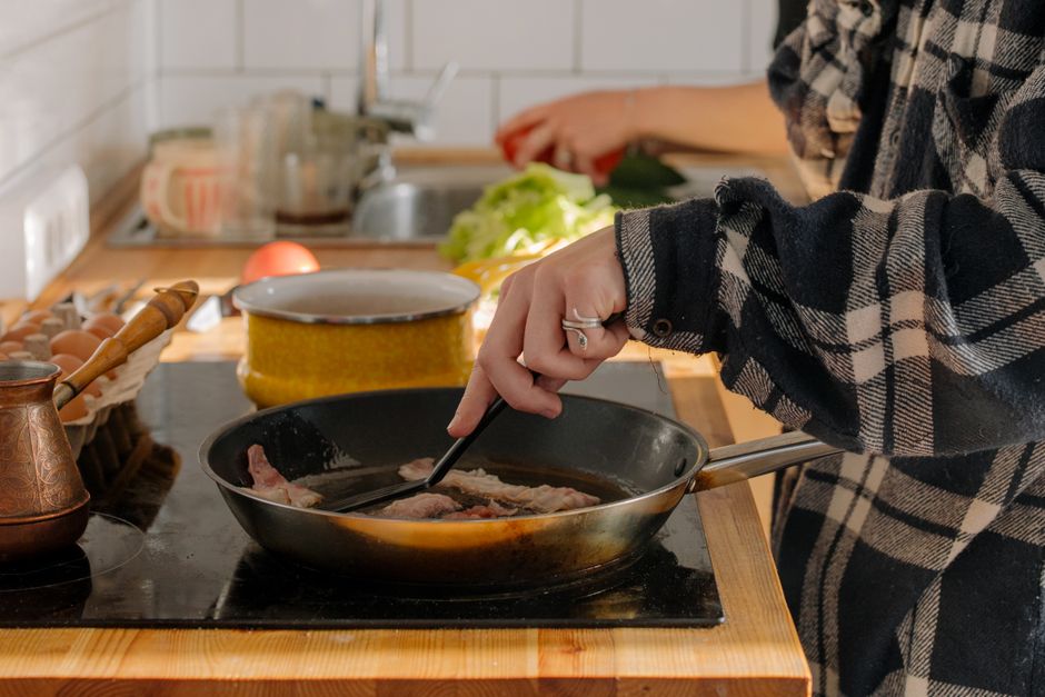 Strips of crispy bacon arranged in a single layer in an air fryer basket, edges curled and deeply browned.
