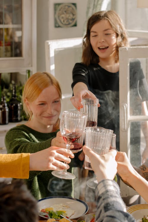 Woman in Green Sweater Holding Drinking Glasses