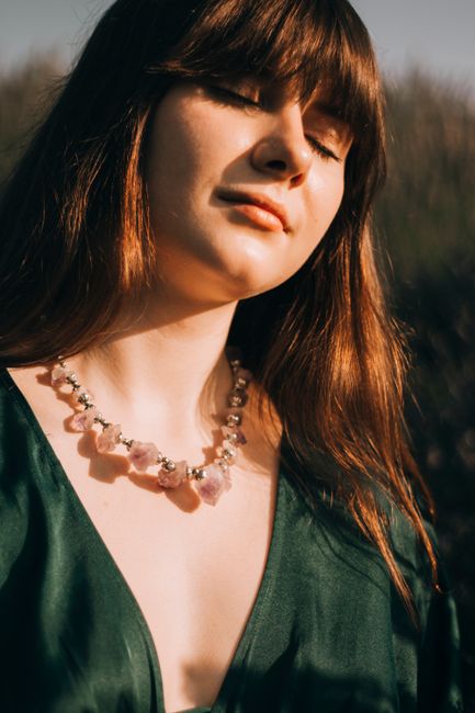 Young charming chubby female with eyes closed and plump lips wearing beads in green provocative blouse