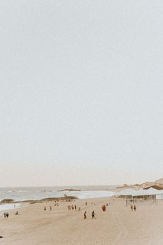 A peaceful beach with people enjoying the sand and sea under a clear sky.