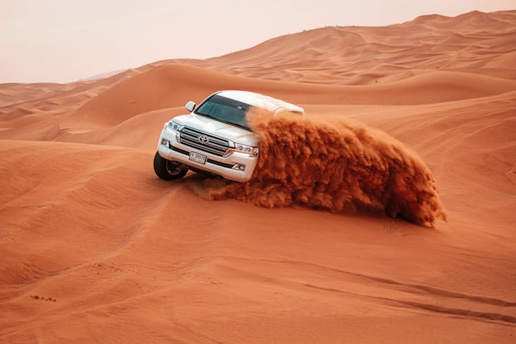 White Toyota Car Driving On Sand Dunes