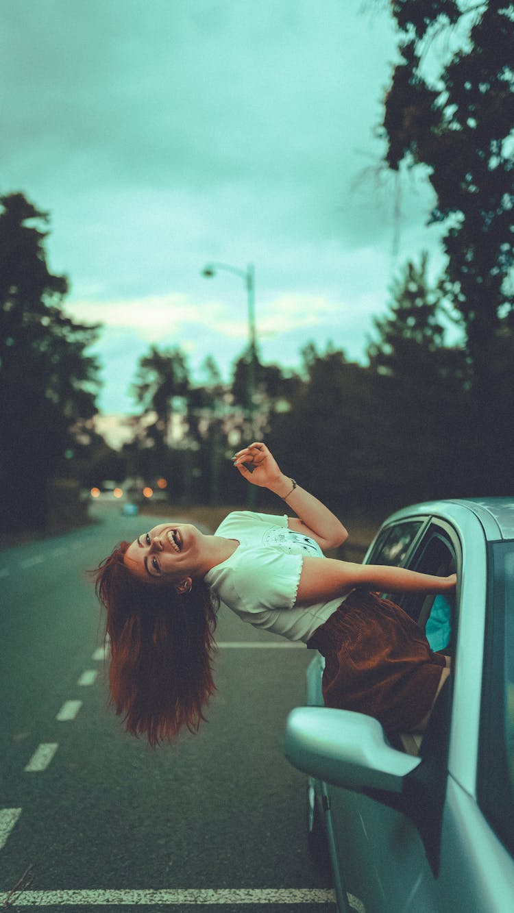 Happy Woman Climbing Out Of Car Window