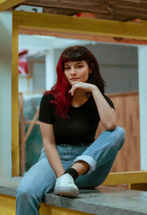Woman in Black T-shirt and Denim Jeans Sitting on a Bench