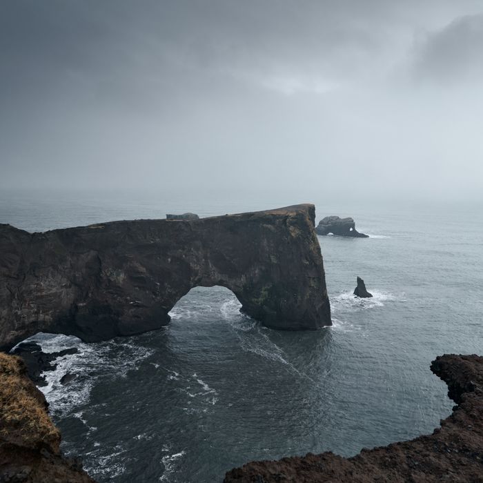 Foggy sea cliffs and rock arch — photo by Valdemaras D. on Pexels