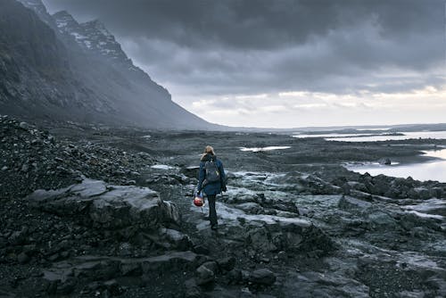 黑色外套和黑色的褲子，站在山附近的岩石地面上的女人