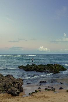 Person standing on rocky shore overlooking the Atlantic Ocean in Bahia, Brazil