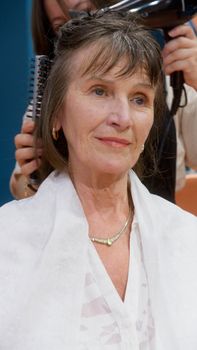 Senior woman enjoying a pampering hair care session in a beauty salon, showcasing self-care.
