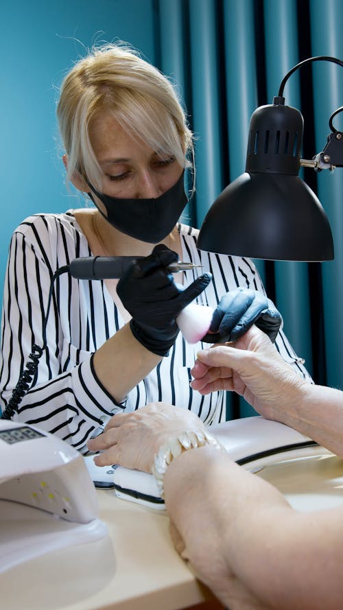 A Manicurist Working while Wearing a Face Mask 