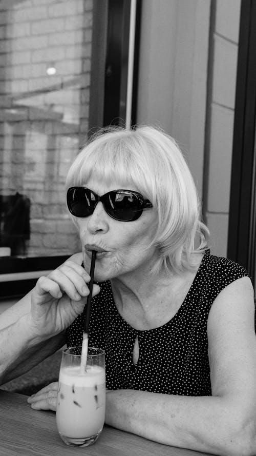 Grayscale Photo of an Elderly Woman Drinking