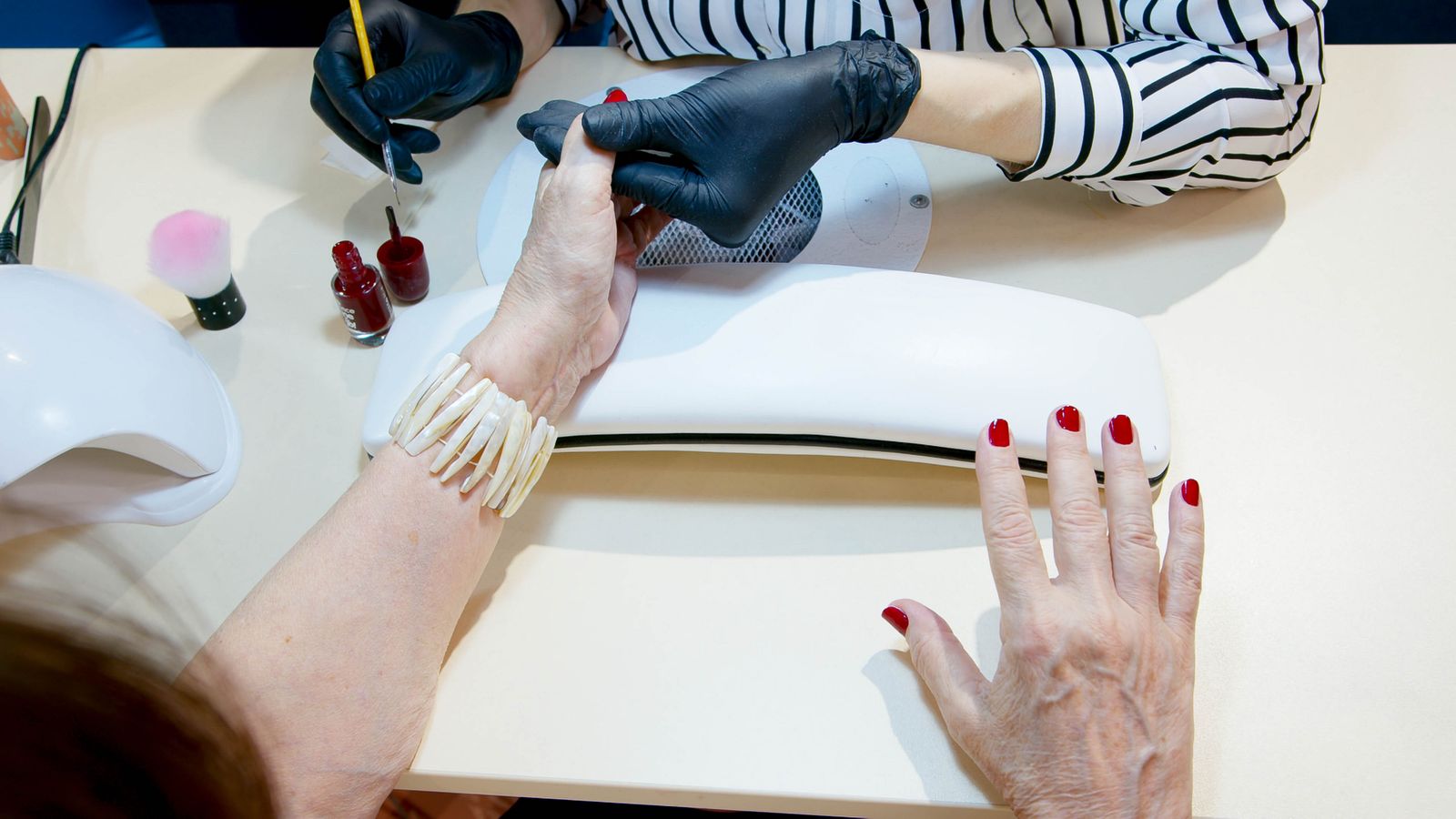 Détail d'une pose de vernis, geste précis en institut