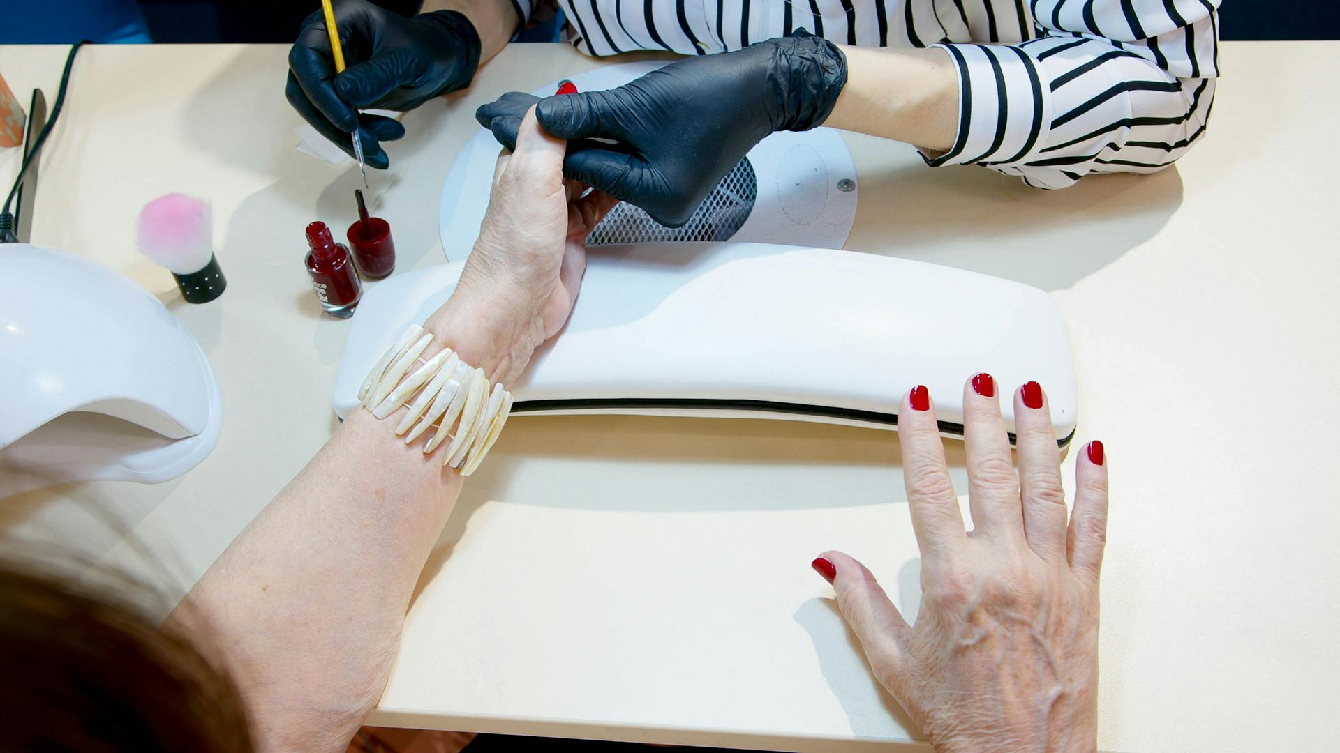 Manicuriste appliquant du vernis à ongles rouge sur un client