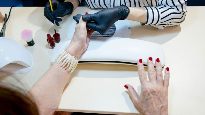 Manicure aplicando esmalte vermelho