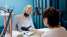 现代沙龙中为客户提供专业指甲护理的美甲师