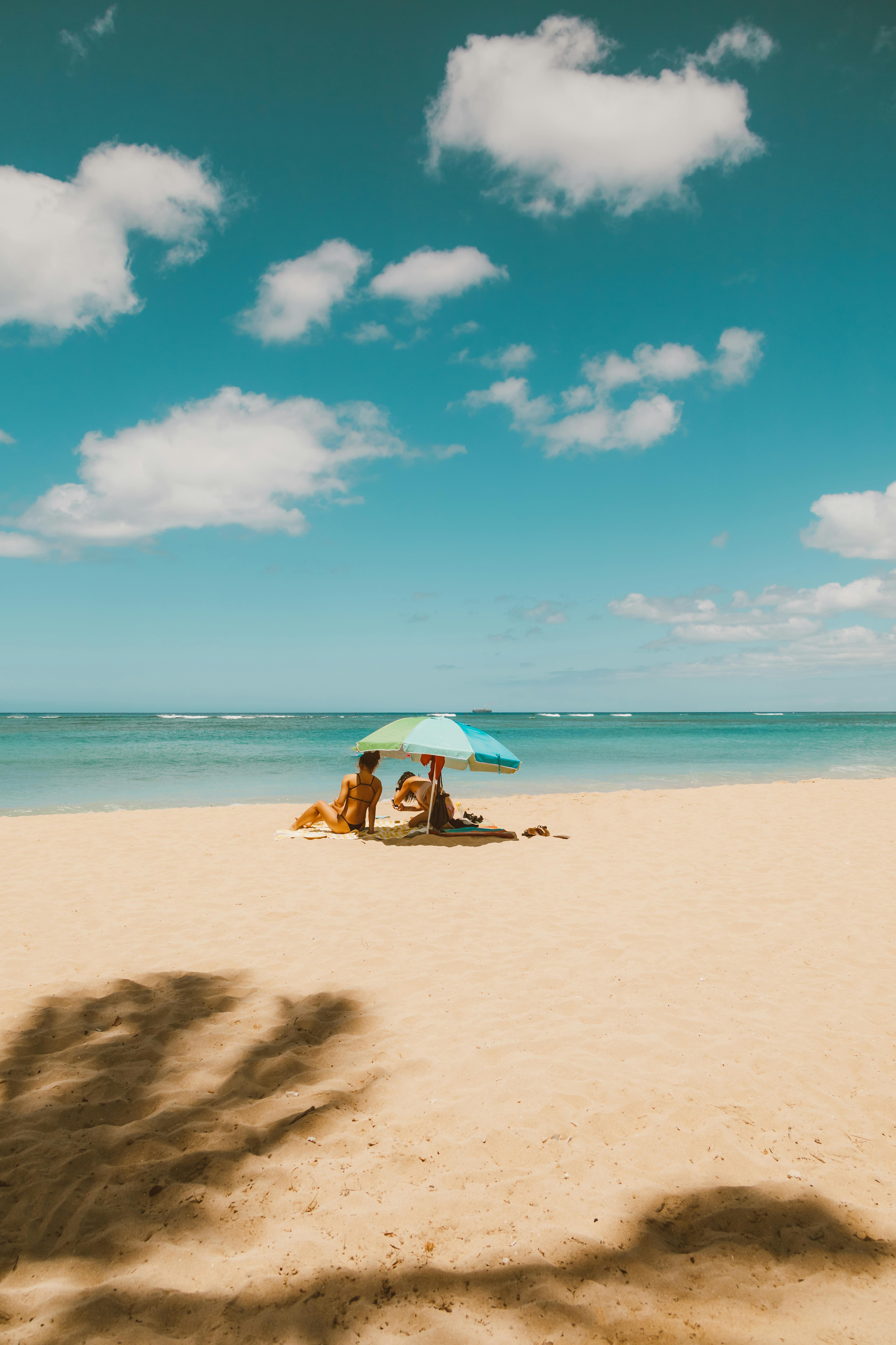 海滩上平静的一天，人们打着彩色的伞，晴朗的天空，平静的大海