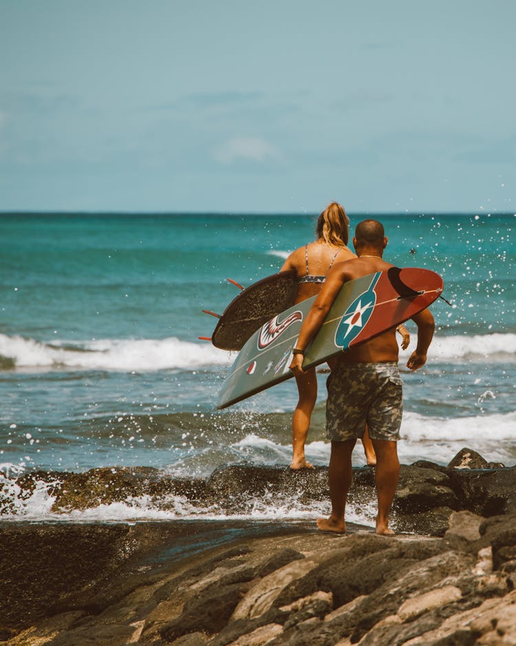 Couple Walking With Surfboards