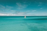 White and Black Lighthouse on Body of Water Under Blue Sky
