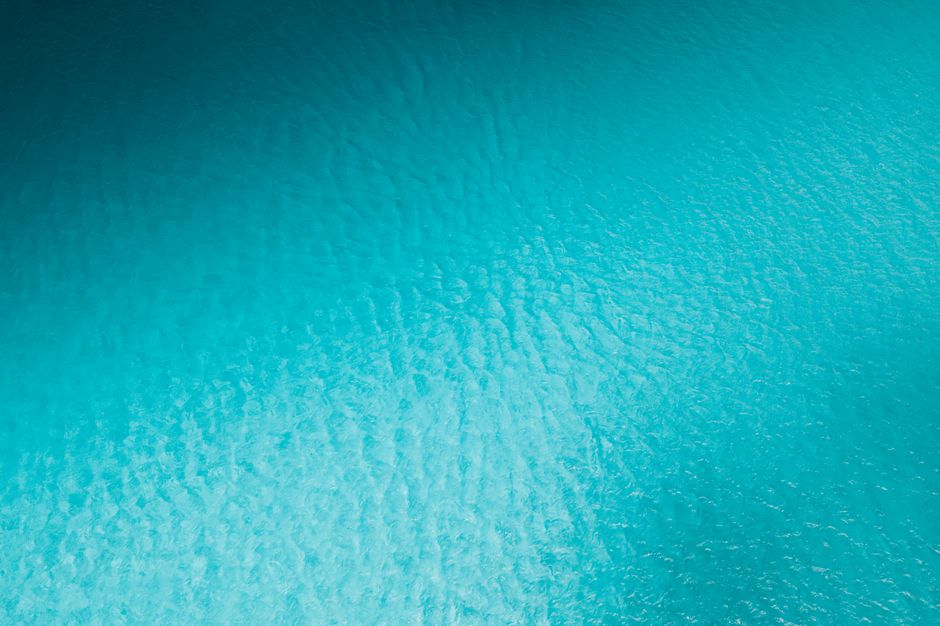 A serene aerial photograph of a textured turquoise water surface, ideal for nature and abstract themes.