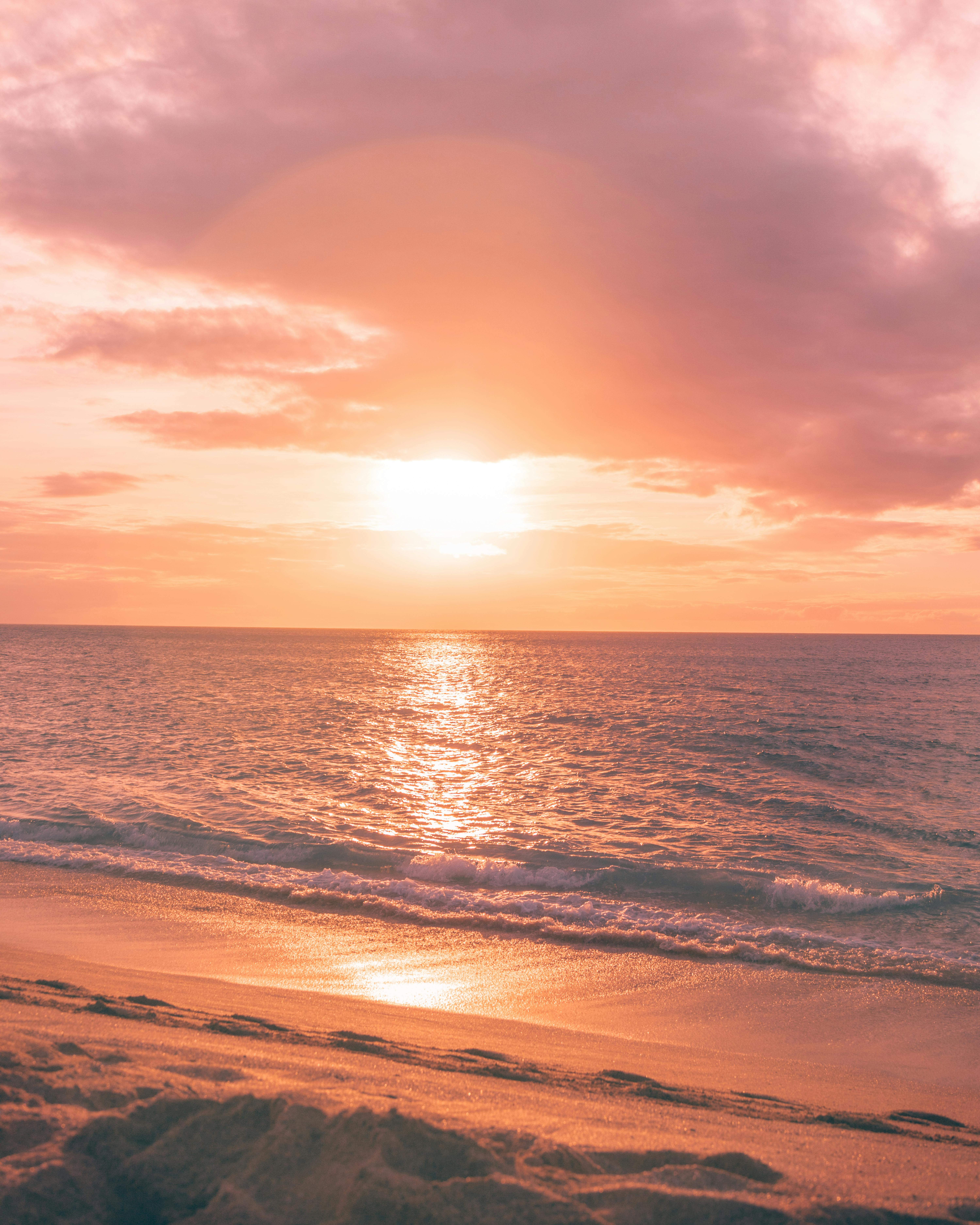 宁静的海滩上美丽的日落，天空粉红色和橙色，倒映在海洋上