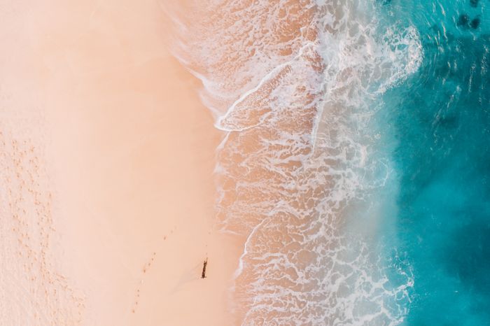 Aerial view of turquoise ocean meeting a sandy beach