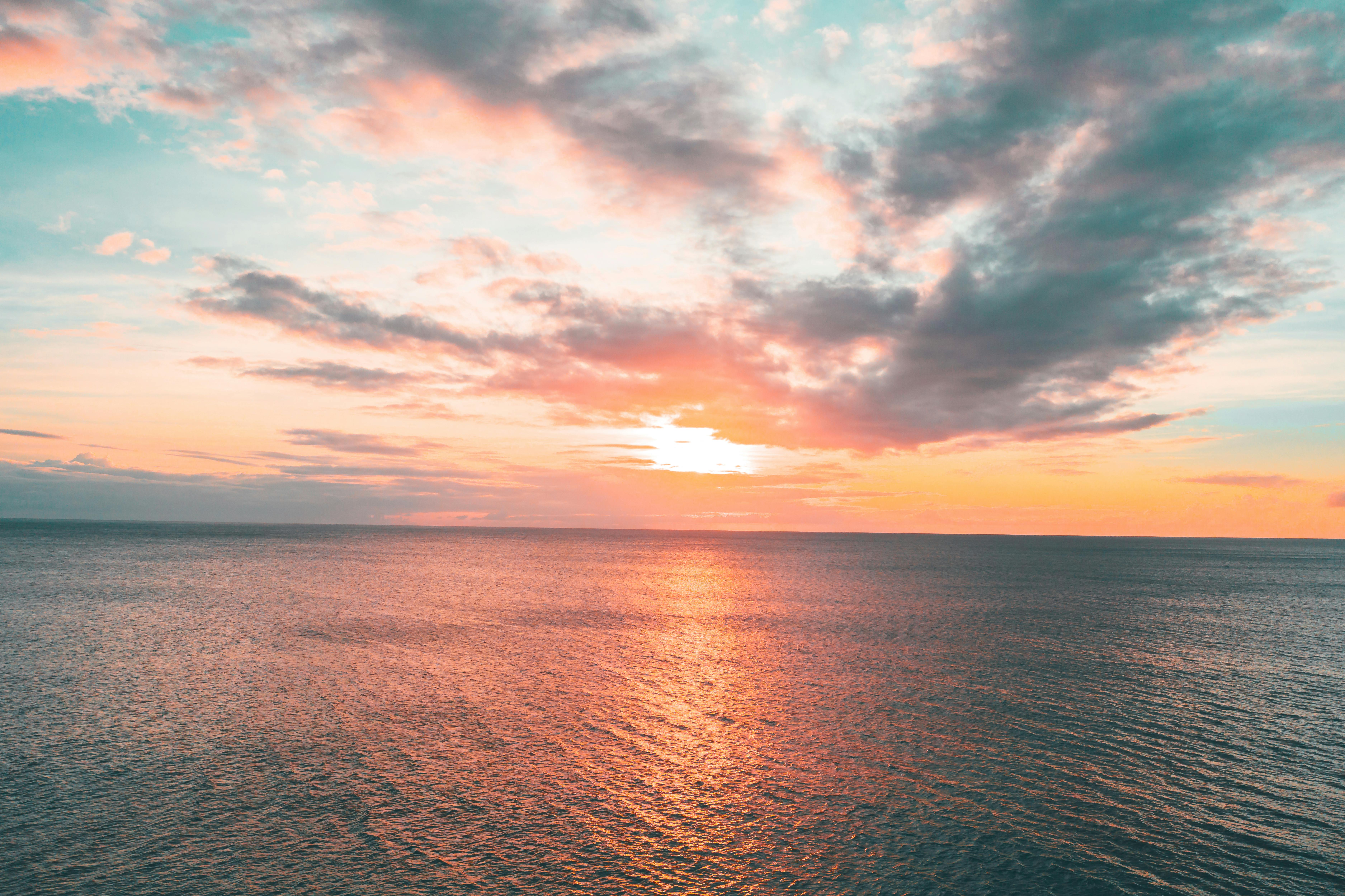 这幅宁静的沿海画面令人惊叹：海洋日落与天空中充满活力的珊瑚色和茶色调交相辉映
