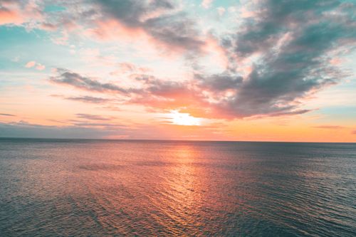 Free Stunning ocean sunset with vibrant coral and teal hues in the sky, perfect for serene coastal imagery. Stock Photo