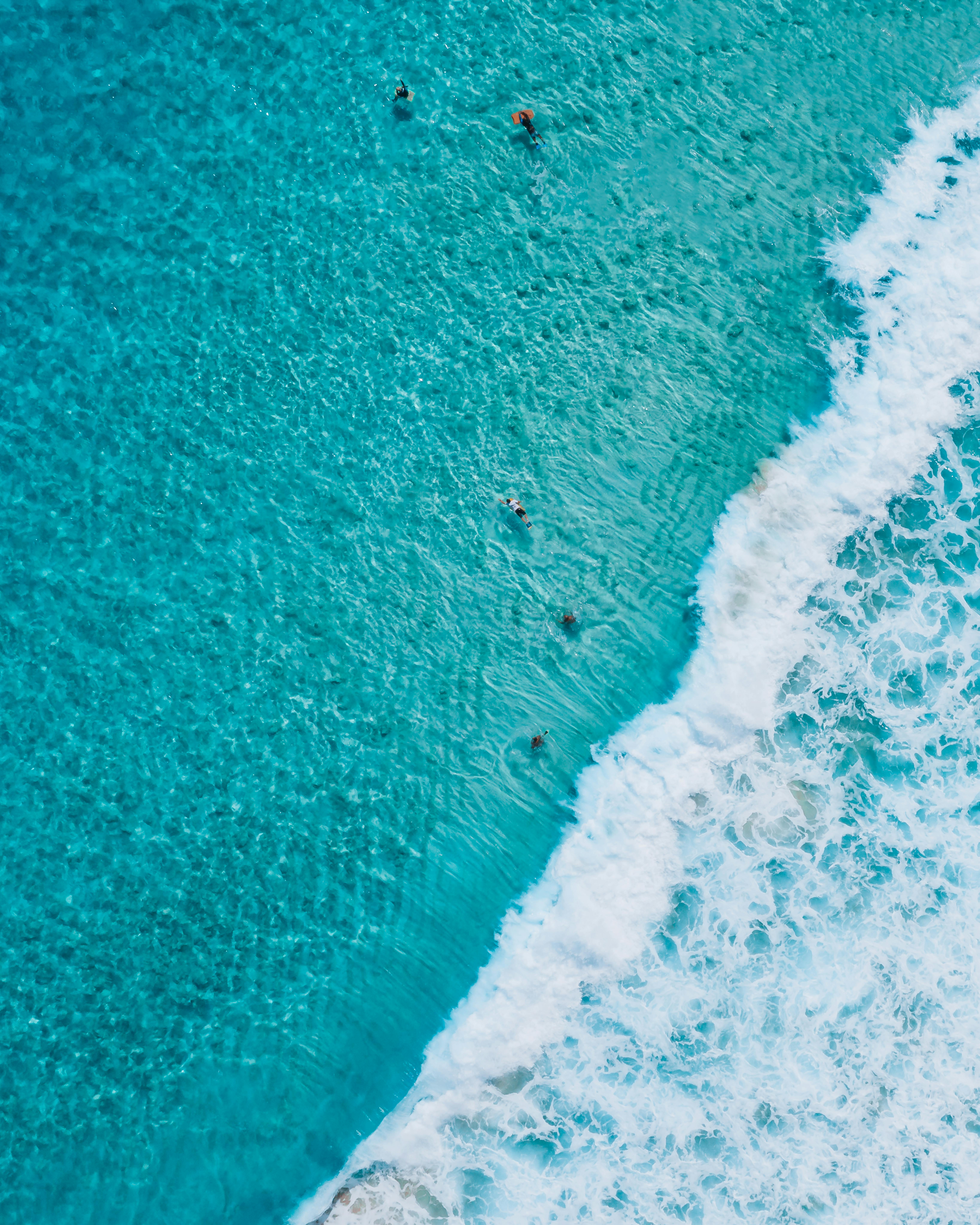 A stunning aerial view capturing swimmers enjoying the turquoise sea waves.
