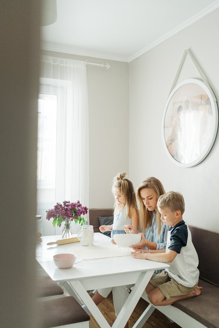 A Woman Preparing Food With Her Kids While Sitting On The Couch