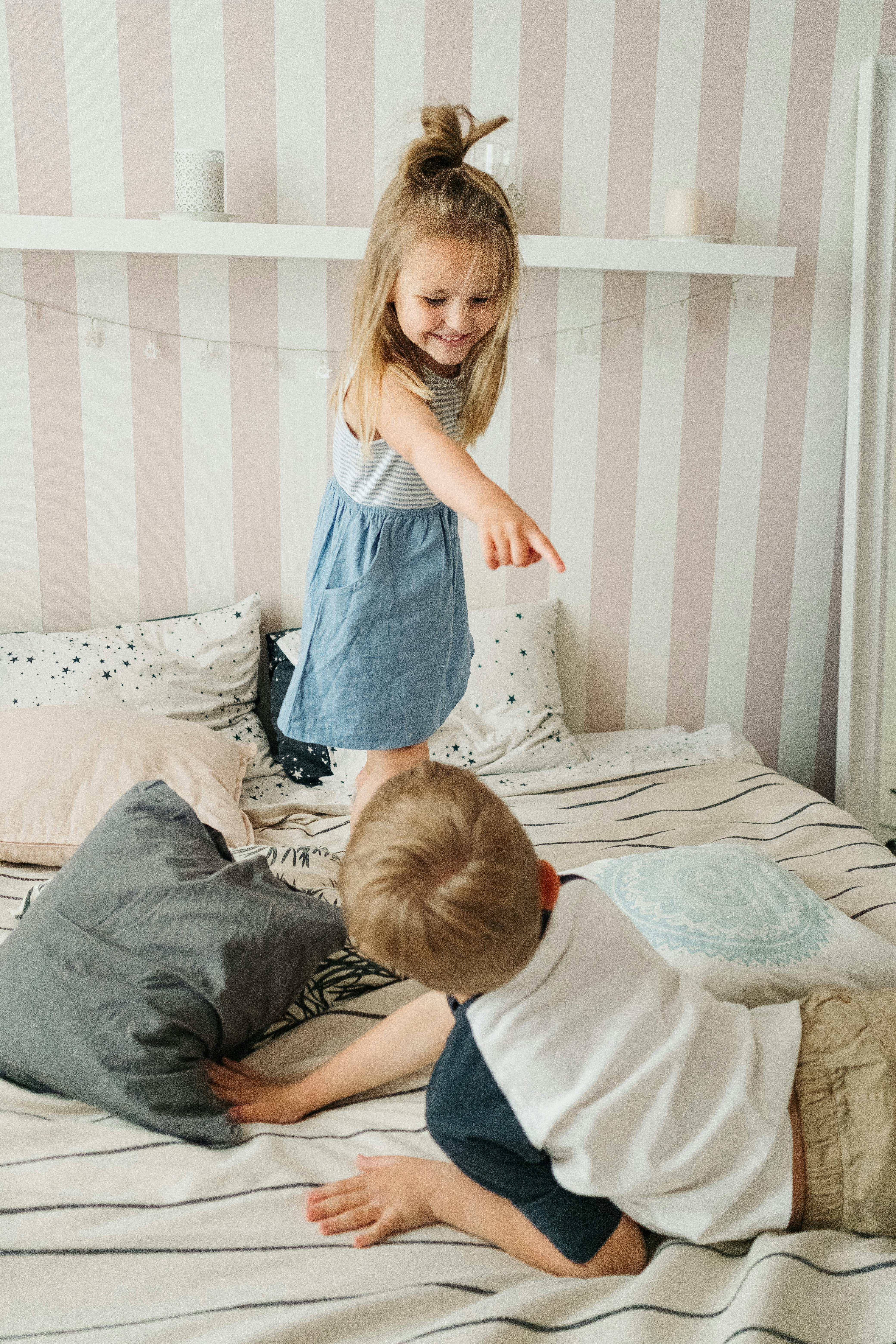 girl in blue tank top and blue denim jeans sitting on bed