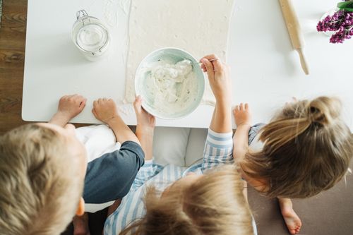 Free Three children mixing ingredients for homemade pastry in a bright kitchen setting. Stock Photo
