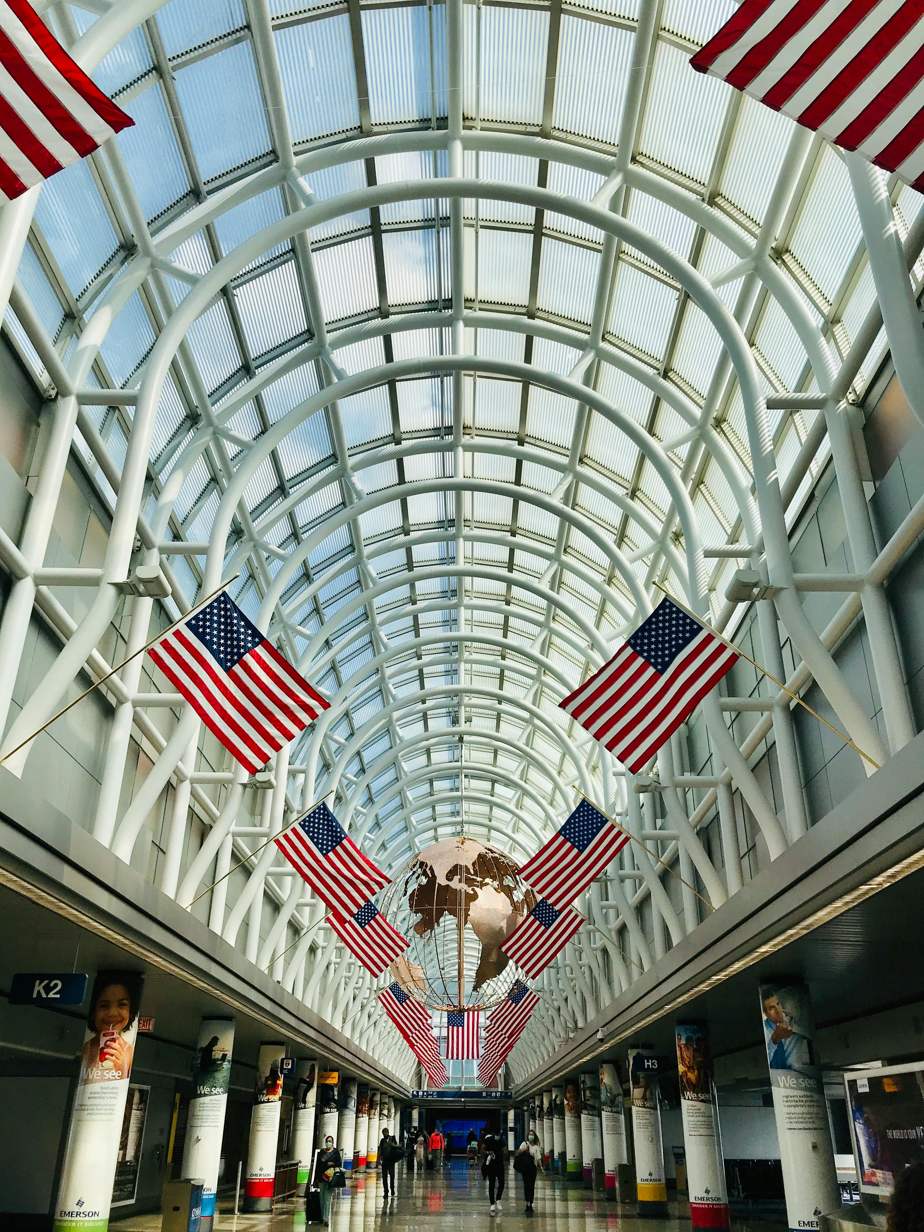 Interior of Chicago O'Hare Airport with American flags and globe sculpture.