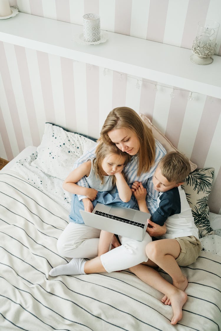 A Family Sitting In Bed Watching On Laptop