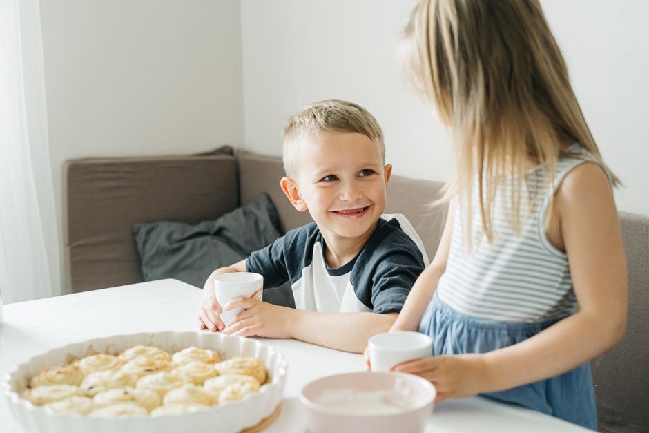Photo by Ivan S on Pexels Smiling siblings sharing a breakfast table with milk and pastries in a cozy home setting. - Photo by Ivan S on Pexels
