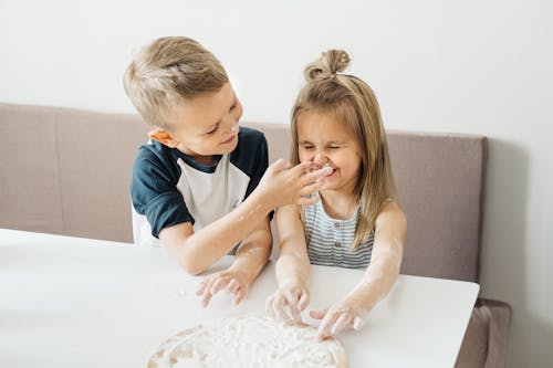 Boy Putting Cream on Sister's Face