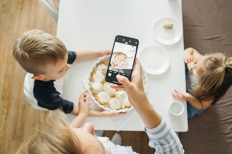 Person Holding A Smartphone Taking Photo Of Food