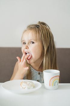 可爱的女孩在室内享用带有彩虹设计的甜点和杯子