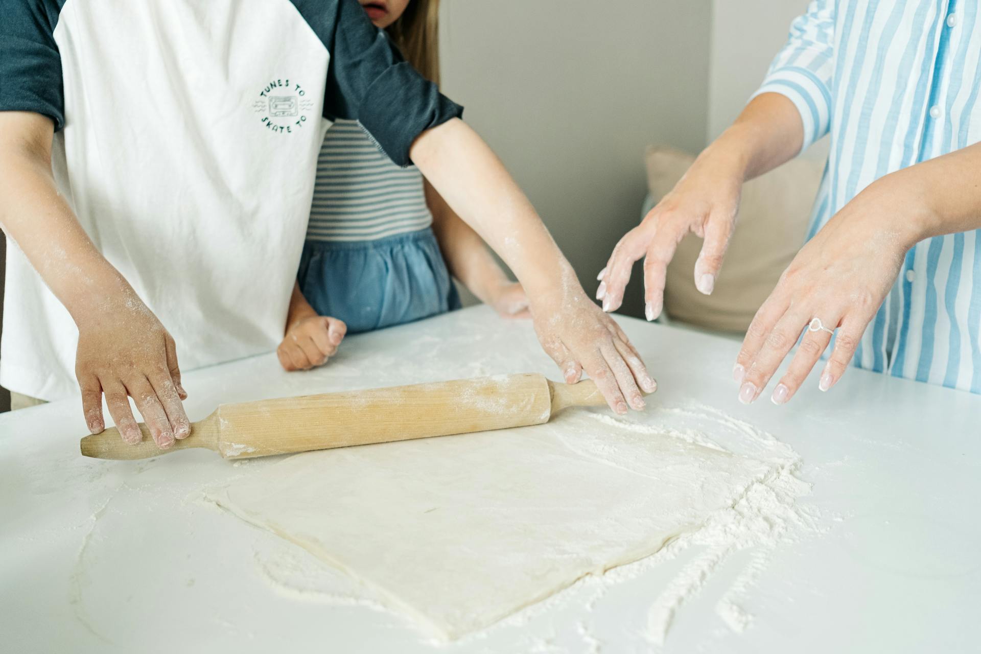 Hands of a Person Using a Rolling Pin on a Dough