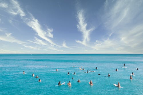 Free Surfers Waiting for Waves on Sea Under Blue Sky Stock Photo