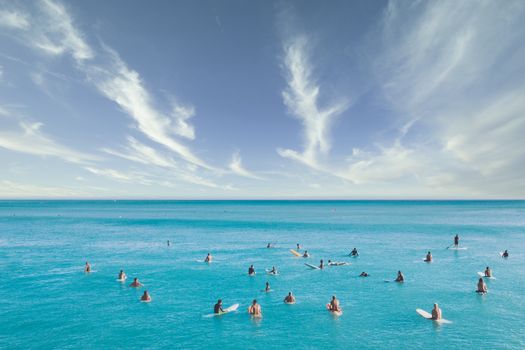 在充满活力的夏日天空下，冲浪者聚集在绿松石水域