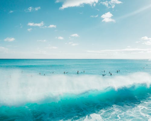 People Surfing on Sea Waves Under the Sky
