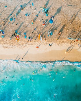 A colorful aerial shot showing beachgoers enjoying a sunny day beside the sea during summer.