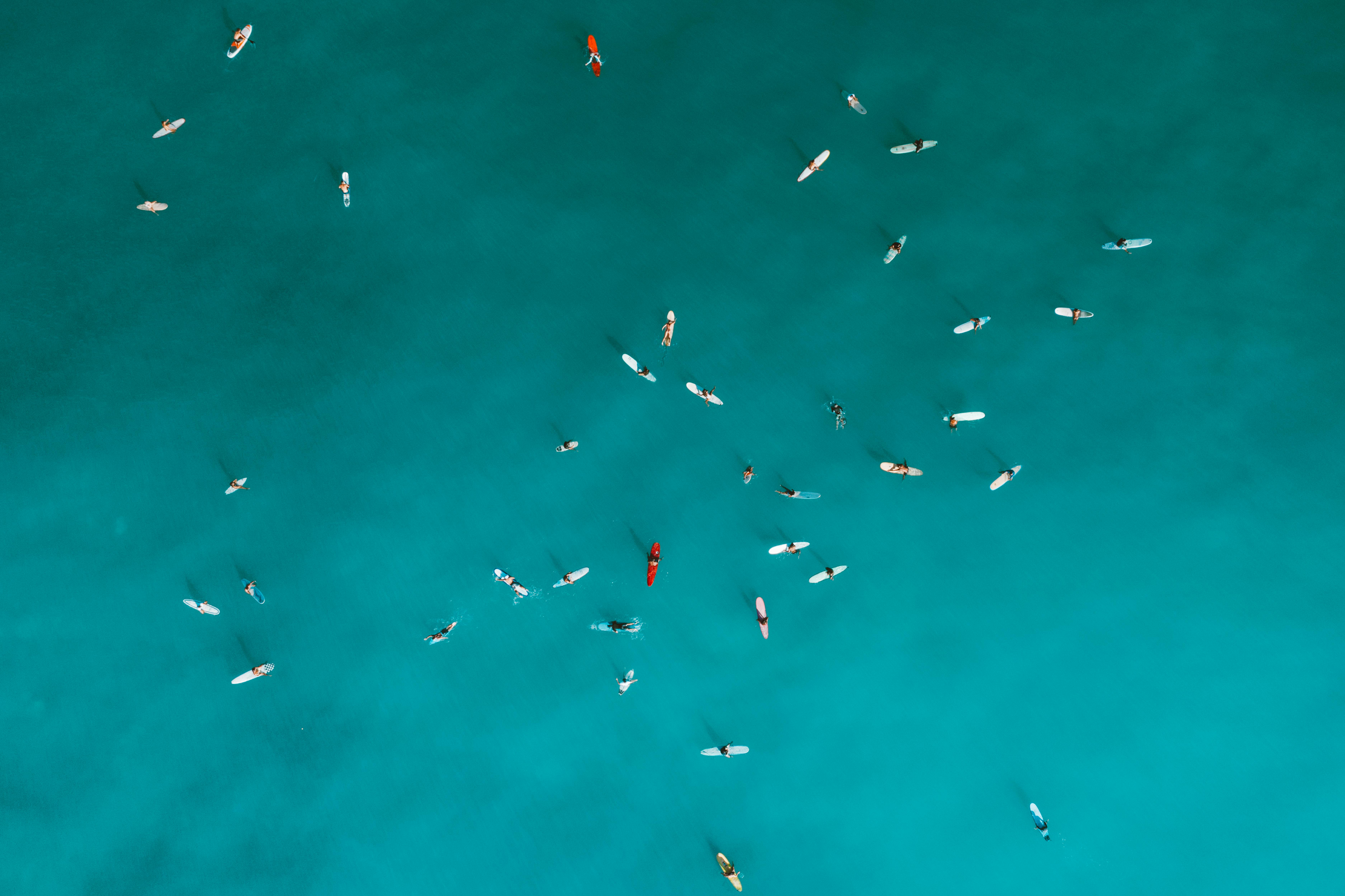 Aerial shot capturing surfers on turquoise ocean water, emphasizing outdoor leisure and water sports.