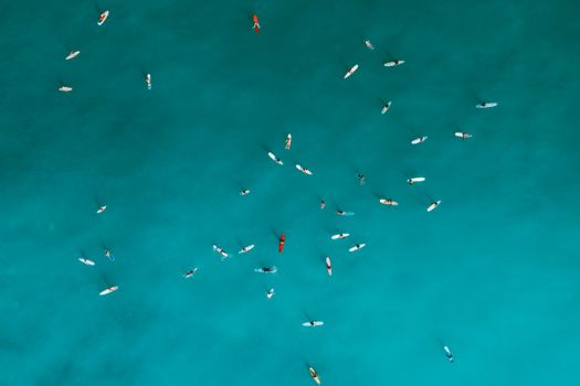 Aerial shot capturing surfers on turquoise ocean water, emphasizing outdoor leisure and water sports.
